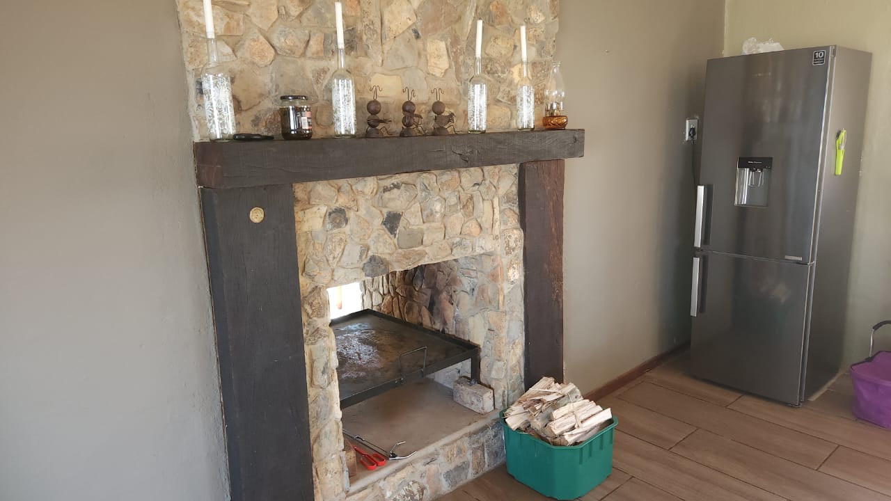 Stone fireplace beside the kitchen fridge